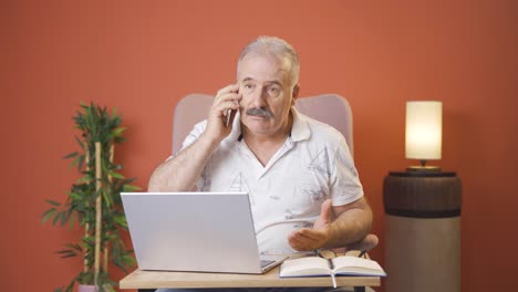 Anciano-Usando-Una-Computadora-Portátil-Hablando-Nerviosamente-Por-Teléfono.